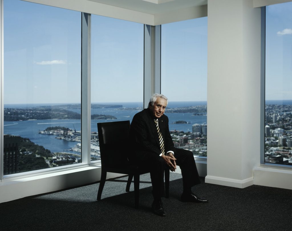 Middle aged man sitting in an empty high rise in a black suit.