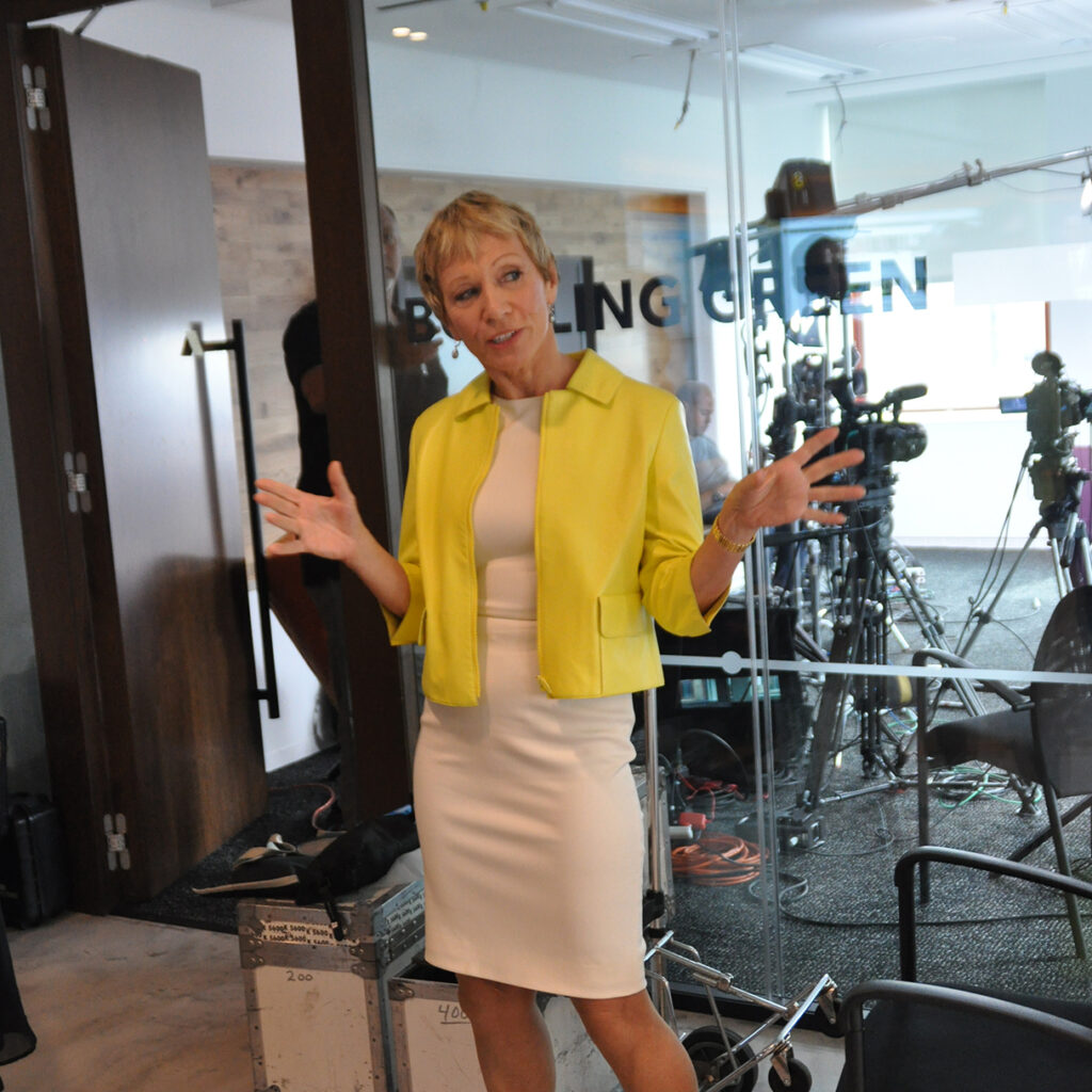 Middle aged blonde woman in corporate wear in the middle of speaking at a photo shoot.